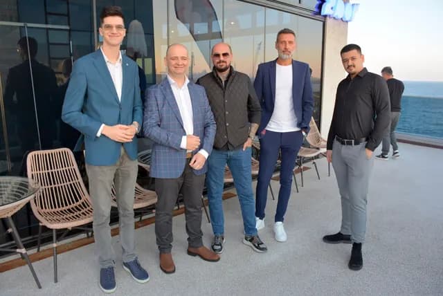 Cinci participanți în ținută de afaceri, reuniți la intrarea Zbor Hub înainte de Conectăm Viitorul.