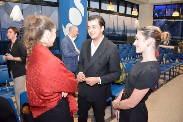 Trei participanți zâmbesc în timpul unei conversații între rândurile de scaune.