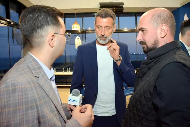 Trei participanți discută într-un grup mic; unul ține un microfon.