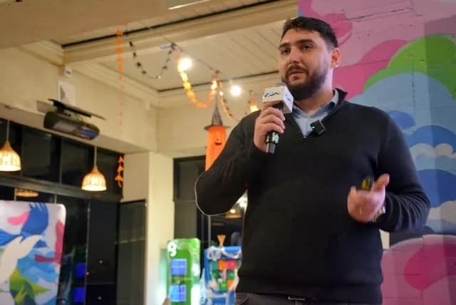 Un vorbitor cu microfon și telecomandă explică un subiect în sala Zbor Hub.