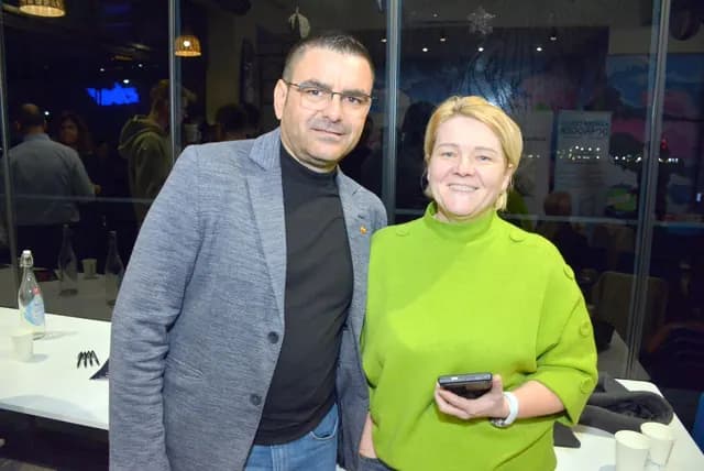Doi participanți zâmbesc pentru o fotografie în sala Zbor Hub.