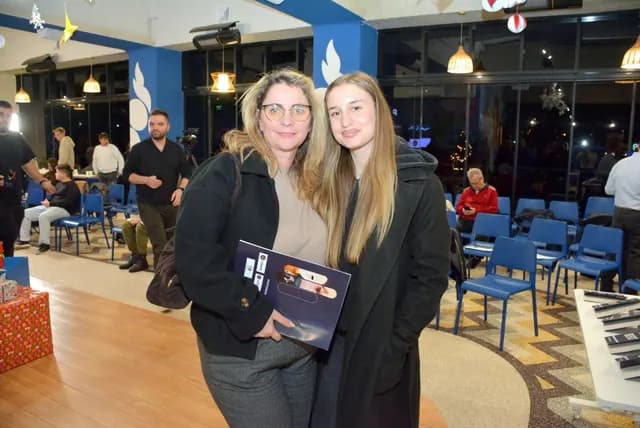 Două participante pozează în sala Zbor Hub; una ține o carte și un material tipărit.