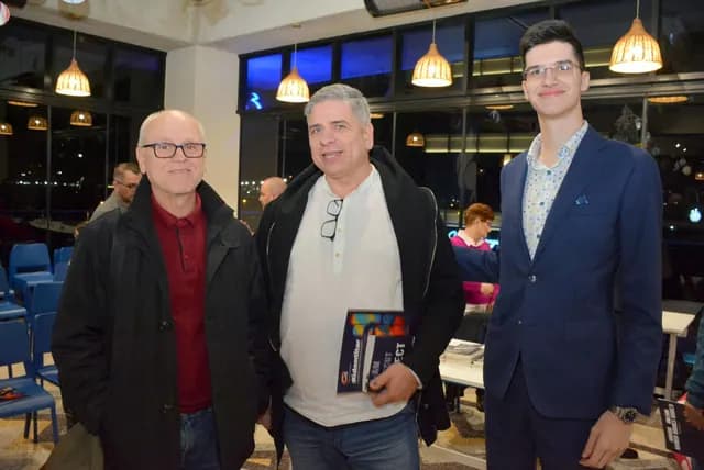 Trei participanți pozează în sala Zbor Hub; unul ține o carte.